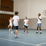 Group of elementary students having PE class with their sports teacher at school gym.